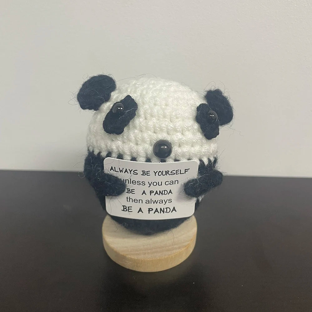 Black and white crochet panda plush holding a sign that says "Always be yourself unless you can be a panda, then always be a panda